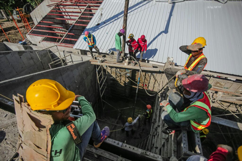 Construction workers wearing helmets and vests on a busy site, focusing on safety and teamwork.
